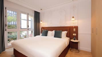 A large bed with white linens, a wooden headboard, and two bedside lamps.