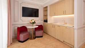 A modern kitchen with two red upholstered chairs, a round table with a vase of flowers, and wooden cabinets with a built-in sink. - Mode Paris Aparthotel (Paris)