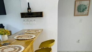 Een keuken met een houten aanrecht, gele stoelen en een wijnfles aan de muur.