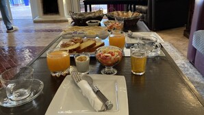 Un bufé de desayuno con diversos alimentos y bebidas, como tostadas, fruta y zumo de naranja.