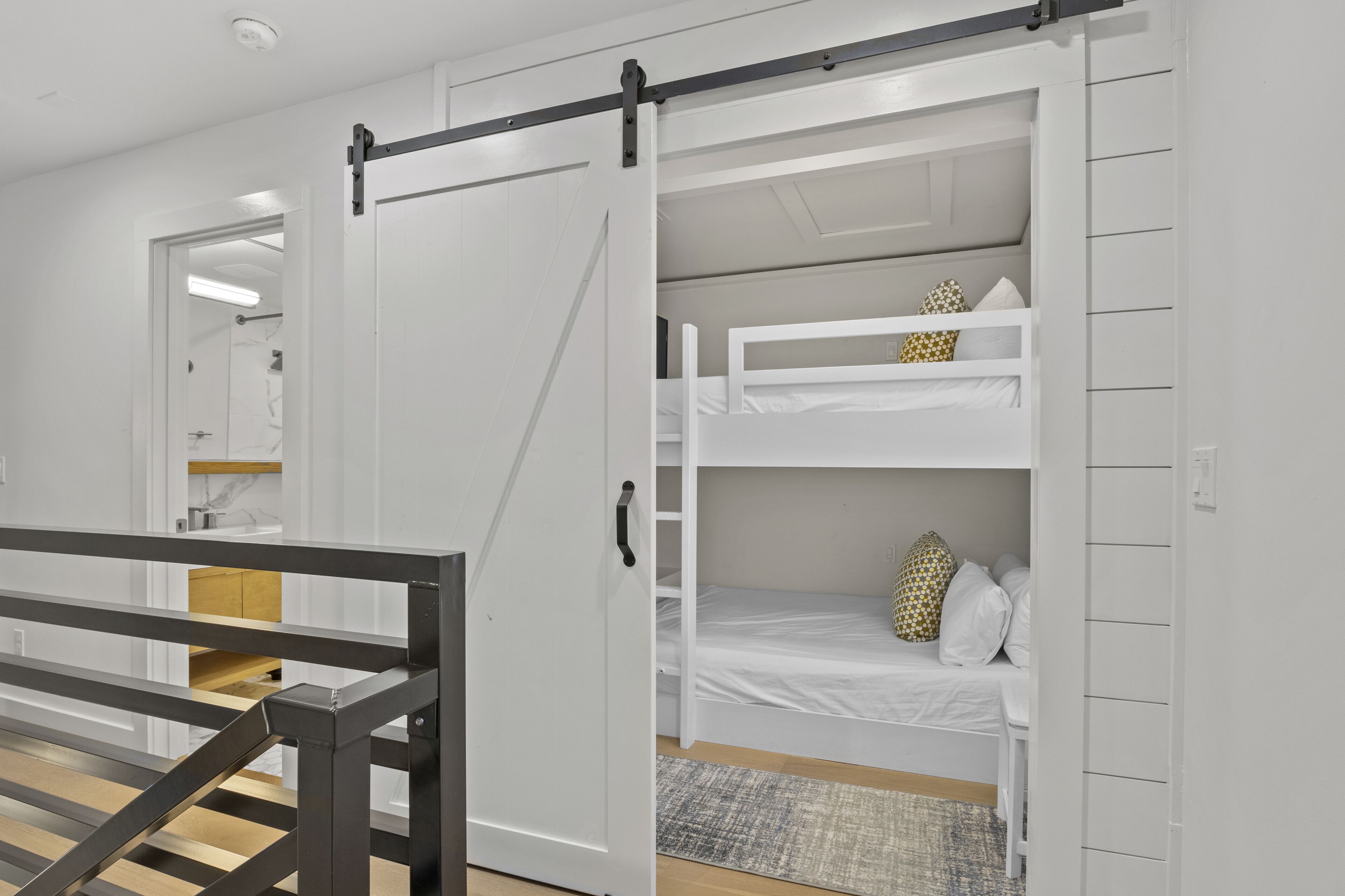 A room with a bunk bed, a wooden floor, and a white door with a black handle.