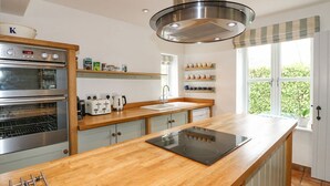 A modern kitchen with stainless steel appliances, wooden countertops, and a large window providing natural light.