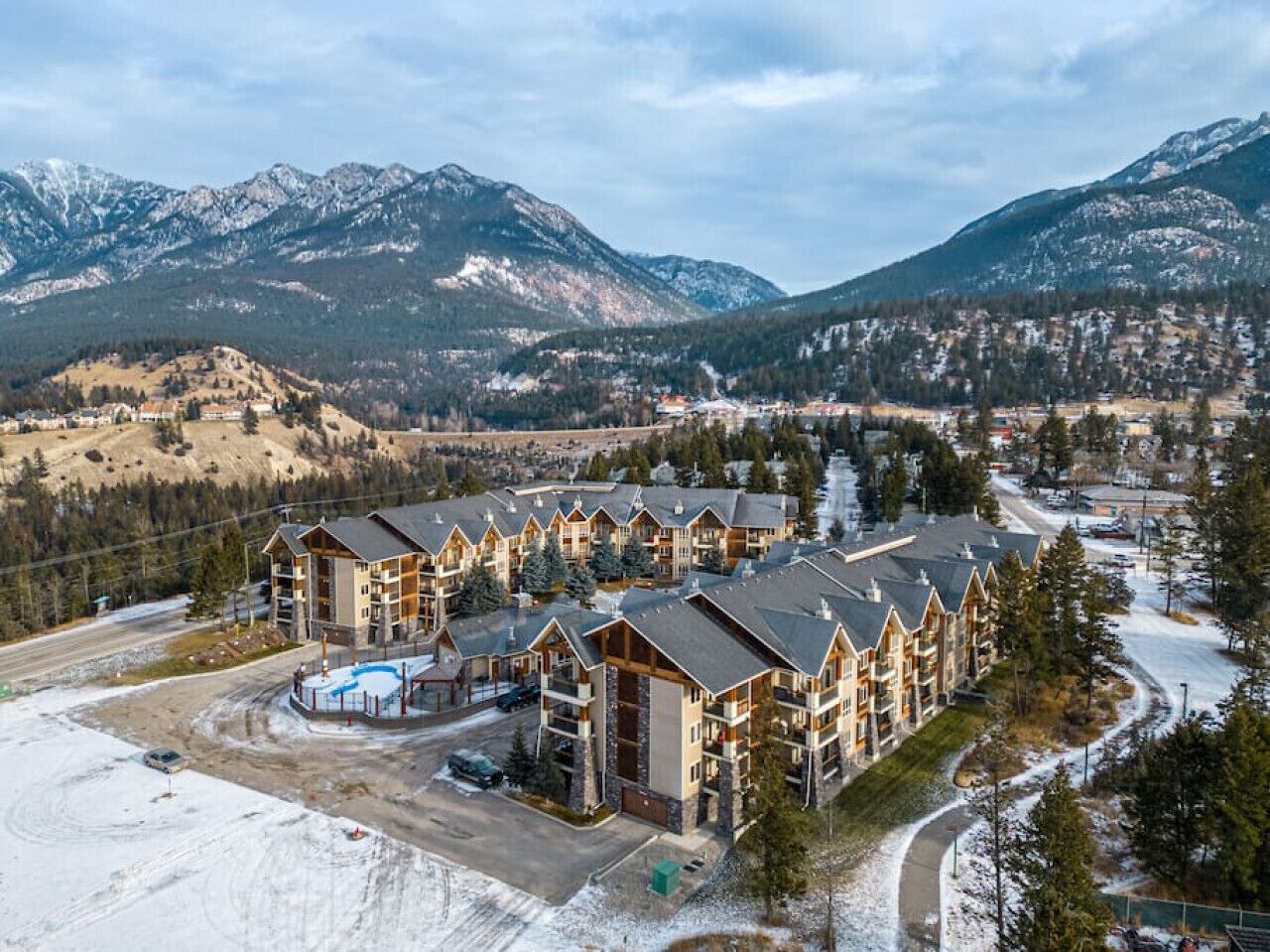 A lodge with multiple buildings, a swimming pool, and a view of snow-covered mountains.