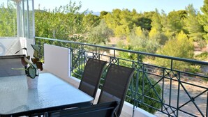 Een balkon met een tafel en stoelen, met uitzicht op een natuurlandschap met bomen en struiken.