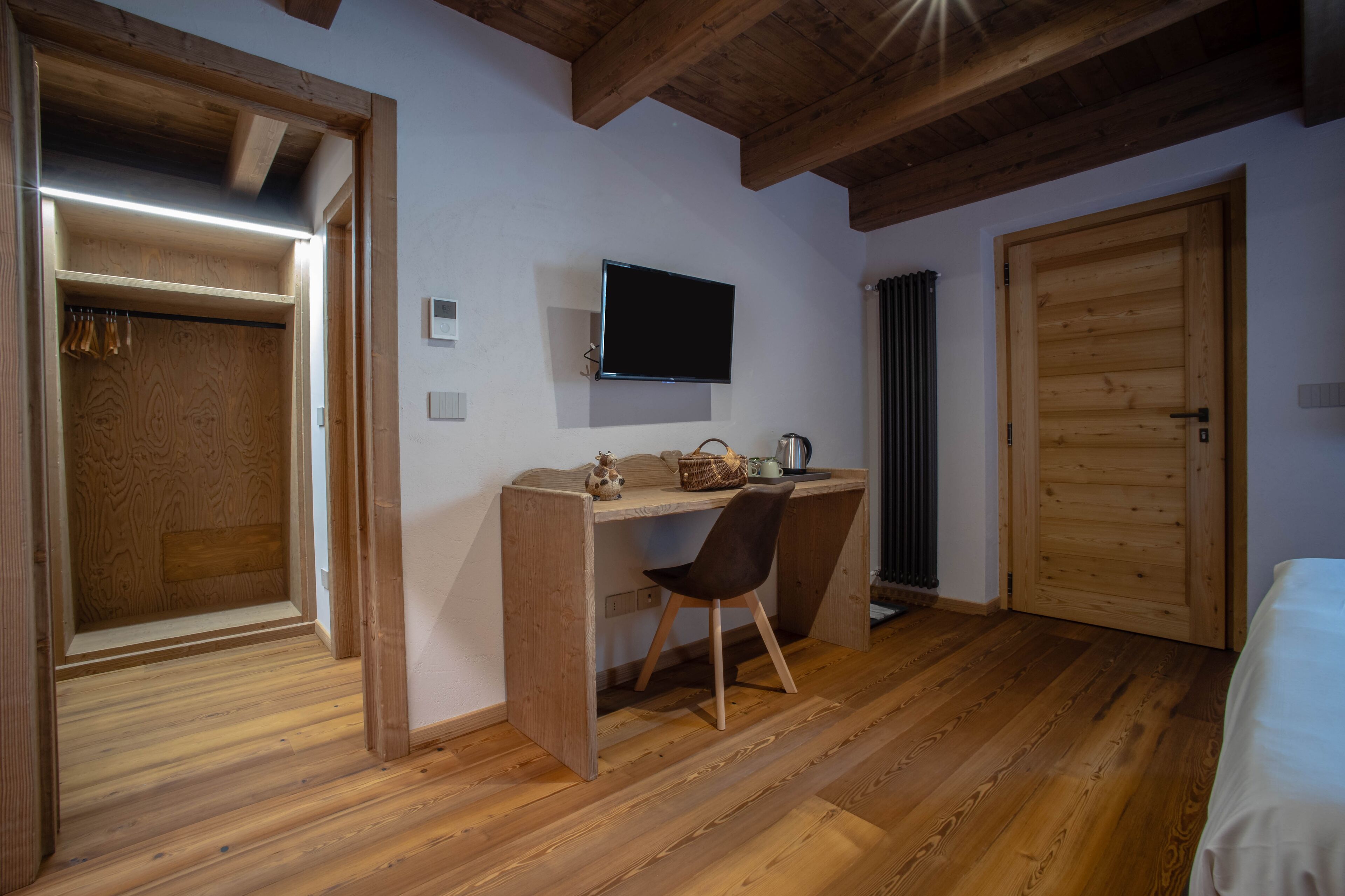 Une pièce avec un bureau en bois, une chaise et un téléviseur fixé au mur.