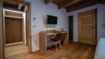 Une pièce avec un bureau en bois, une chaise et un téléviseur fixé au mur.