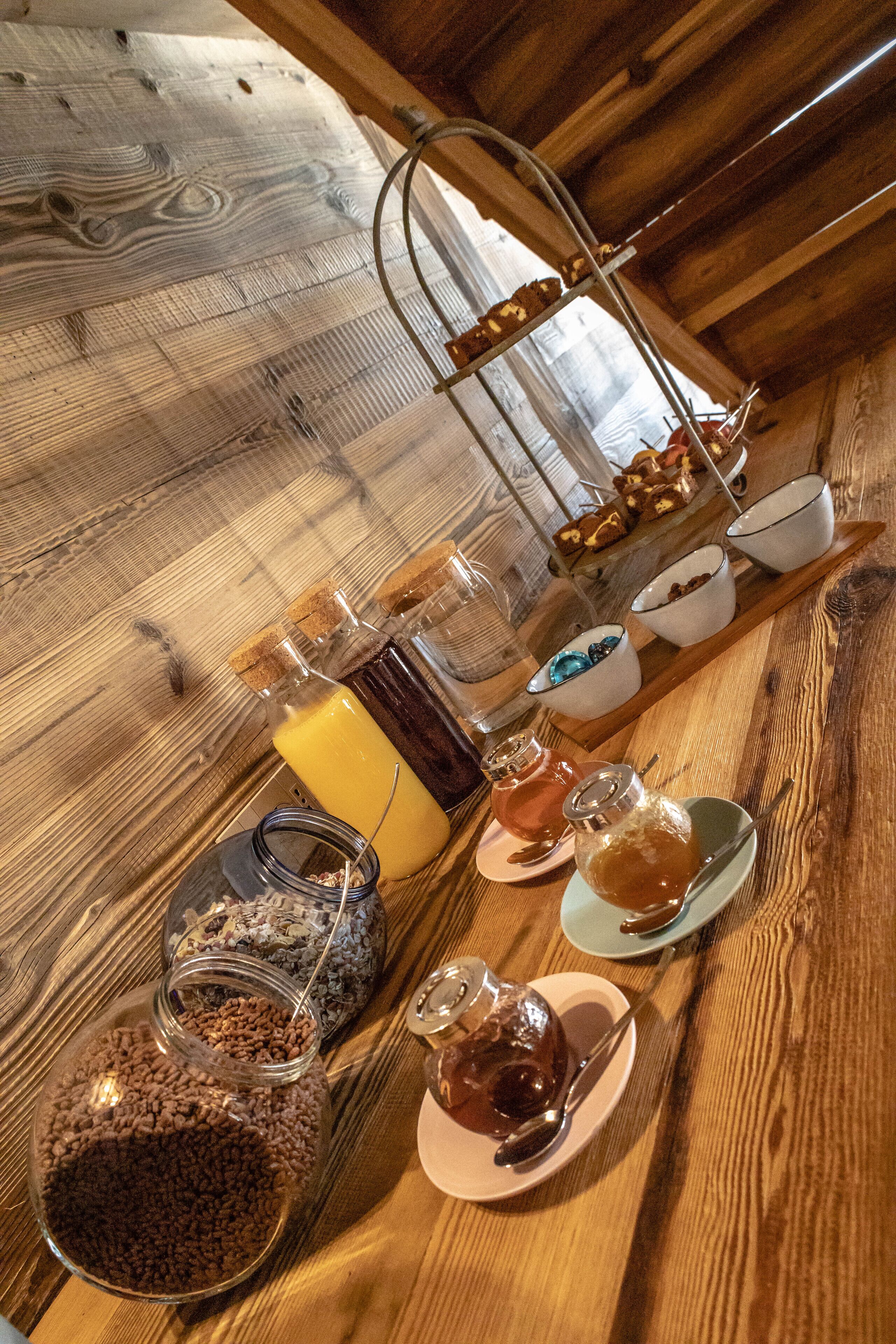 A breakfast buffet with various food items and condiments on a wooden table.