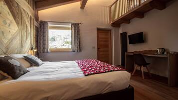 Une chambre à coucher avec un lit, un bureau, une chaise, un téléviseur et une fenêtre avec des rideaux.