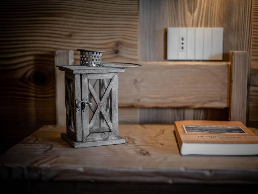 A rustic wooden table with a metal lantern and a book.