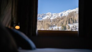 Een kamer met een raam dat uitkijkt op een besneeuwd berglandschap.