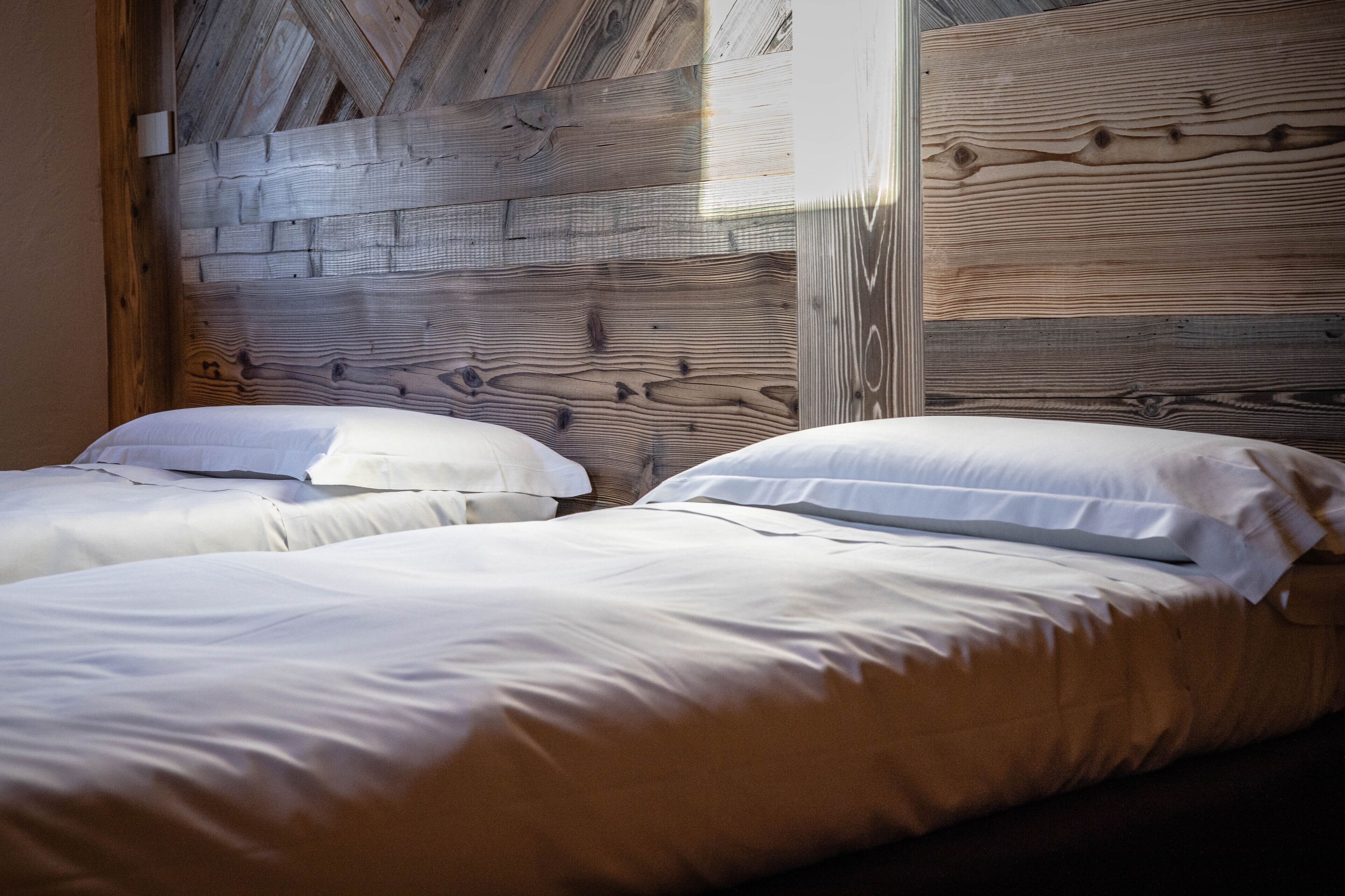 A room with two beds, wooden headboard, and a window.