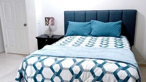 A bedroom with a bed, a nightstand, and a door. - Exclusive apartment in Mxl 3 (Mexicali)