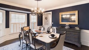 A dining room with a chandelier, dark walls, and a large window. - Colonial with a contemporary flare. Come relax and unwind! (Lilburn)