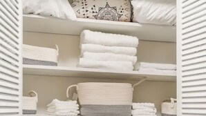 A neatly organized storage unit with shelves holding folded towels, a patterned pillow, and storage baskets. - Colonial with a contemporary flare. Come relax and unwind! (Lilburn)