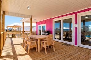 Um deck de madeira com mesa, cadeiras, churrasqueira e uma placa com a inscrição 'A melhor piscina'.