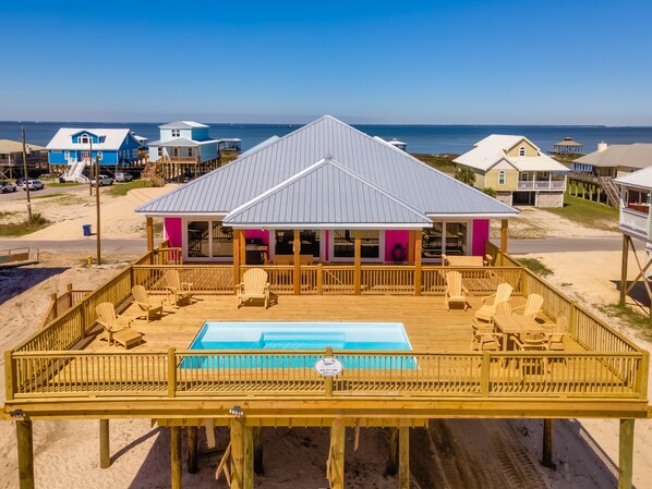 Una casa de playa con piscina, terraza de madera y vista al océano.