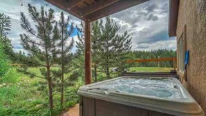 A hot tub in a covered outdoor area with a view of trees and a cloudy sky. - Remote Cabin Family Fun Hot Tub (Florissant)