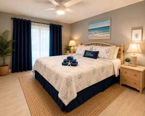 A bedroom with a bed, a nightstand, a lamp, a ceiling fan, a window with curtains, a plant, and a painting on the wall.
