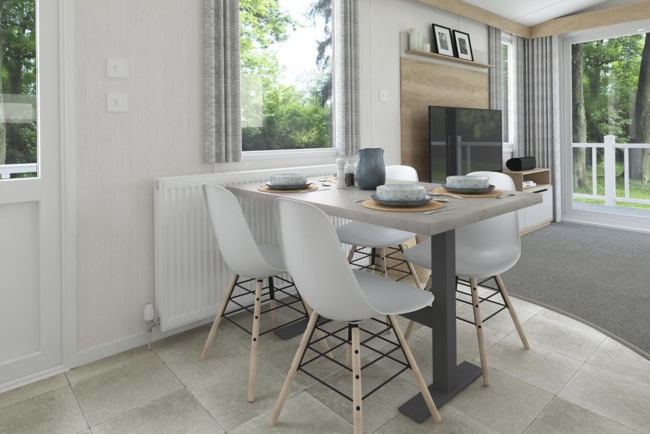 A modern dining area with a white table, four white chairs, and a large window with a view of greenery.