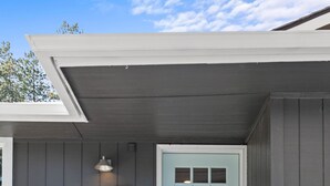 A light blue door with a 'WELCOME' sign, wooden steps, and a light fixture above.