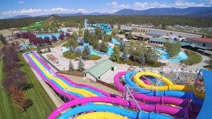 An aerial view of a water park with multiple slides and pools, surrounded by trees and buildings.