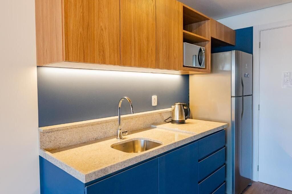 A kitchen with a stainless steel sink, a kettle, and a built-in oven.