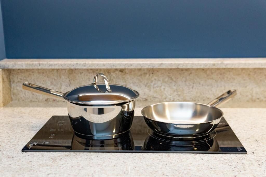 A kitchen with a stove, a pot, and a pan on a induction cooktop.