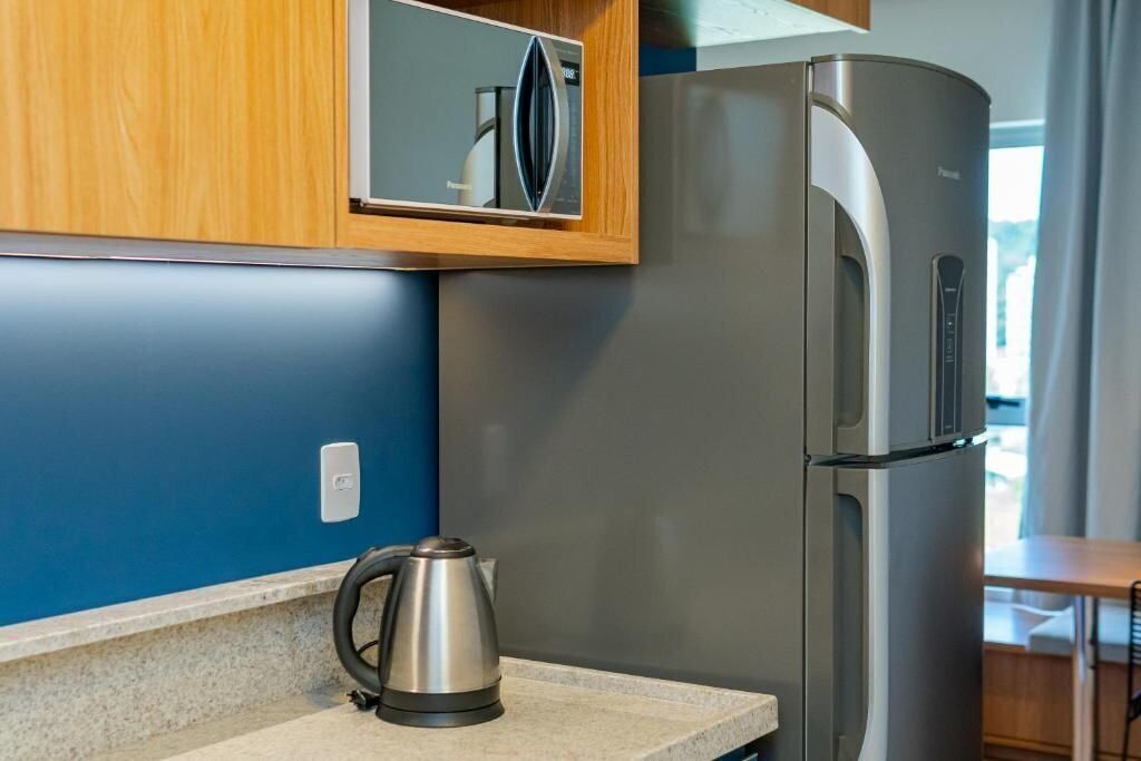 Una cocina moderna con un refrigerador de acero inoxidable, una tetera y armarios de madera.