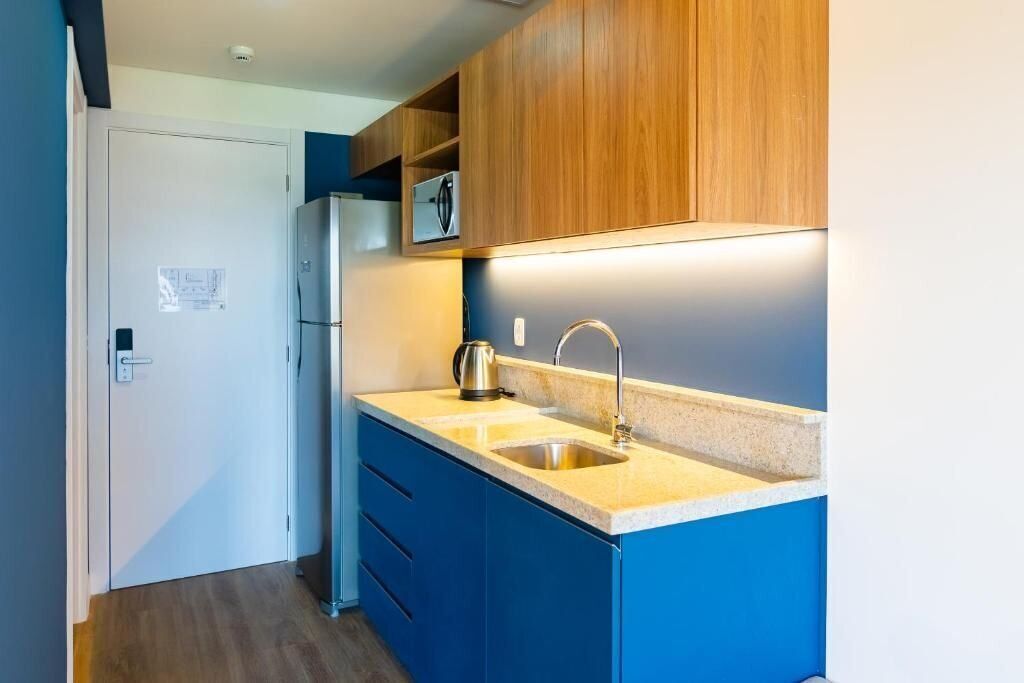A compact kitchen with blue cabinets, a stainless steel sink, and a built-in microwave.