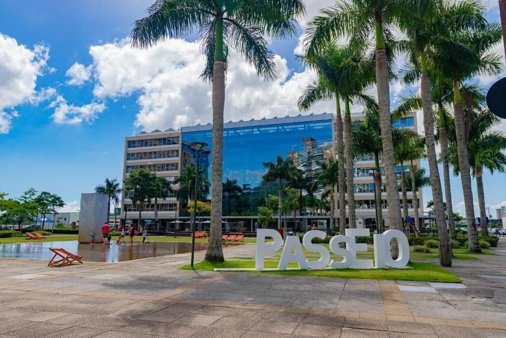 A modern building with a glass facade and palm trees in front.