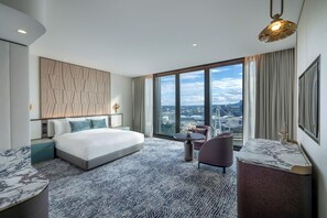 Ein modernes Hotelzimmer mit einem großen Bett, einem Schreibtisch und Blick auf die Stadt.