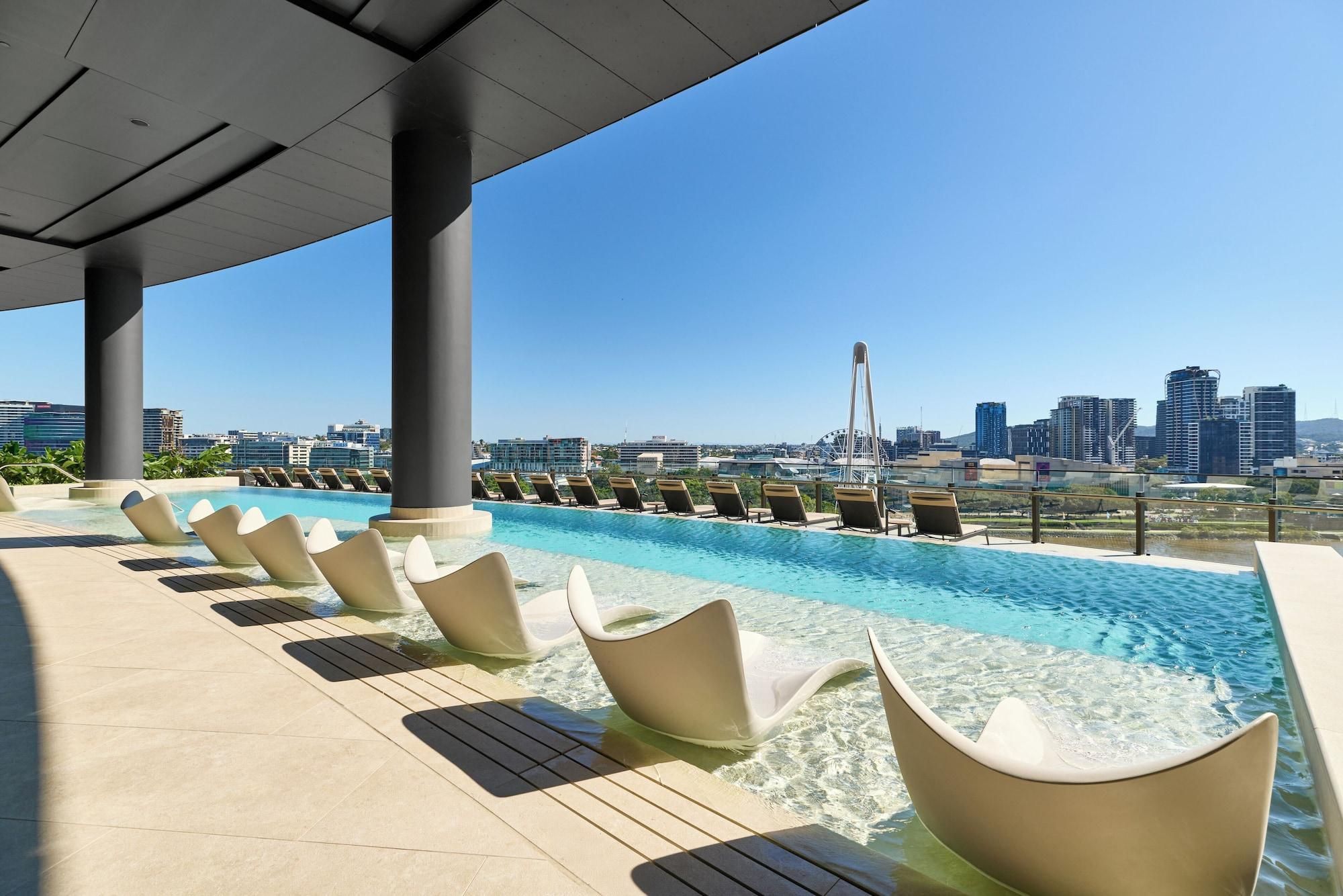 A rooftop pool with lounge chairs and a cityscape view.