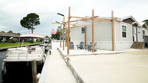 A waterfront property with a dock, a covered outdoor seating area, and a house with a porch. - ☀️WATERFRONT W BOAT ACCESS PCB. 3BD 2BA. PRIVATE CANAL RIGHT TO THE BAY (Panama City Beach)