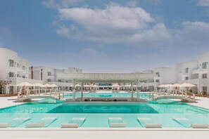 A pool area with multiple swimming pools, lounge chairs, and umbrellas. - Tanoak Ain Sokhna Hotel (Ataqah)