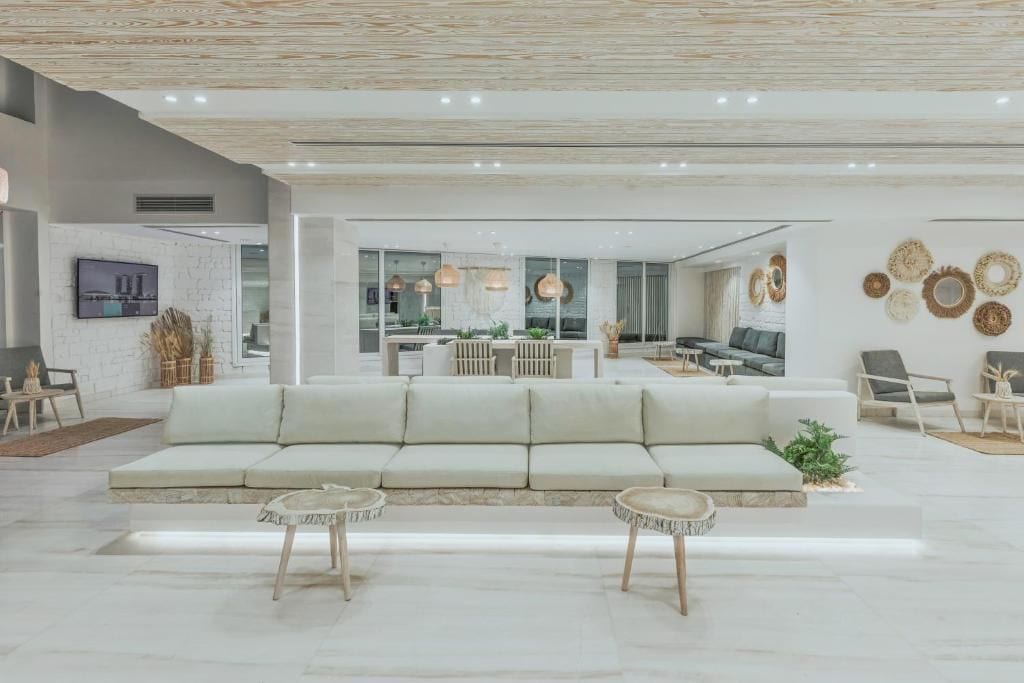 Een moderne woonkamer met een bank, twee bijzettafels en een eethoek met een tafel en stoelen.