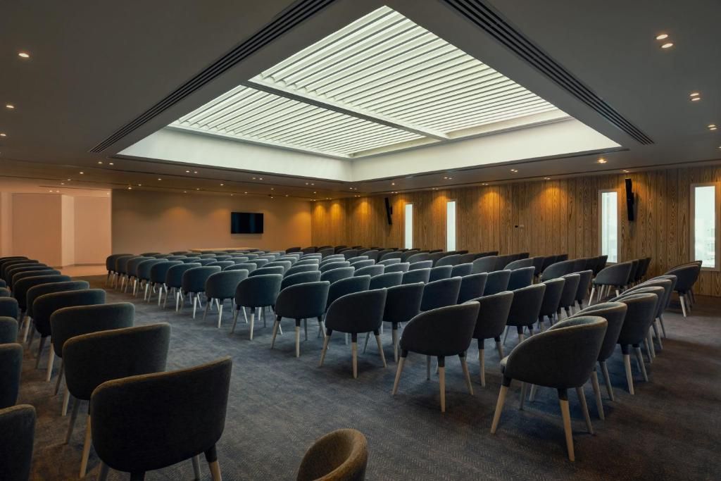 A conference room with rows of chairs, a skylight, and wooden panel walls.