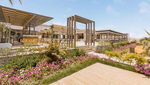 Un resort moderno con terraza de madera, mobiliario exterior y una variedad de plantas y flores.