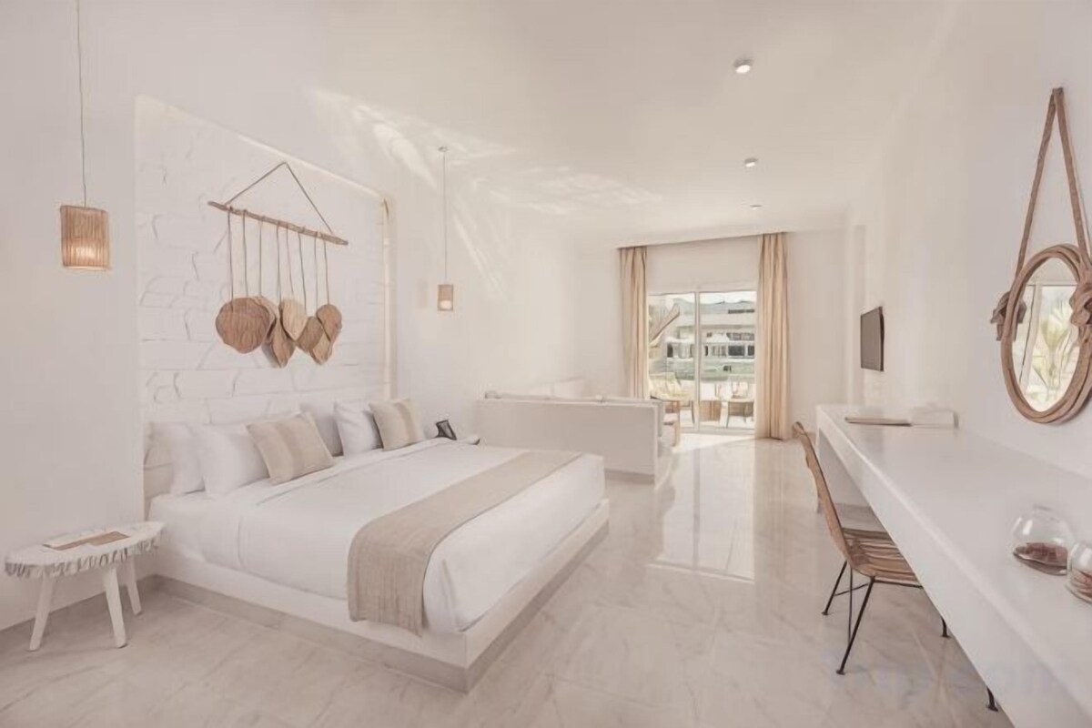 Ein modernes Schlafzimmer mit einem großen Bett, Nachttischen und Blick auf die Stadt.