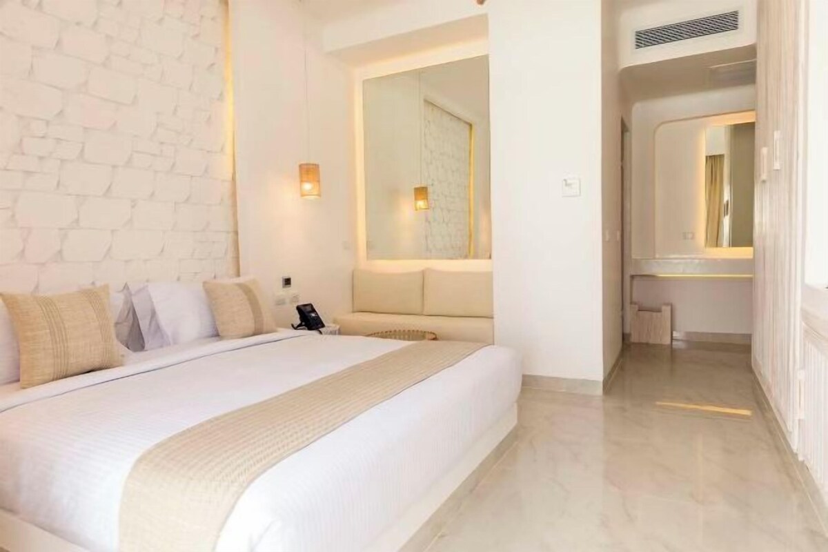 Une chambre d’hôtel avec un grand lit, un miroir, une table de chevet et un mur orné d’un motif texturé.