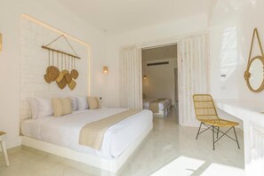 Un dormitorio amplio con una cama grande, una mesita de noche, una silla y una lámpara fijada a la pared.