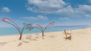 A beach with a hammock, swings, and a small table.