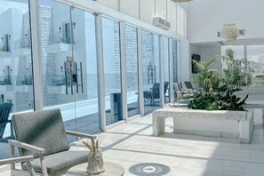 A modern hotel lobby with a glass wall, seating area, and a reception desk.