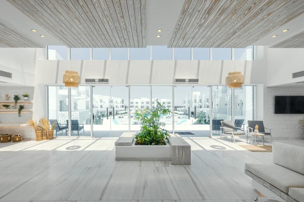 Een ruime lobby met een grote glazen wand, een centrale plantenbak en zithoeken.