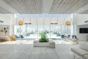 Eine großzügige Lobby mit einer großen Glaswand, einem zentralen Pflanzenbeet und Sitzbereichen.