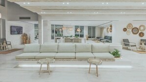 Una sala de estar moderna con un sofá, dos mesitas auxiliares y un comedor con mesa y sillas.