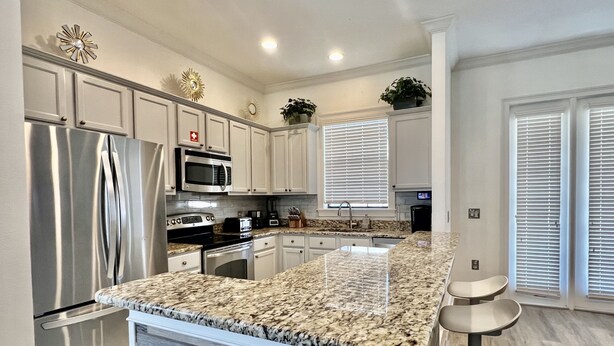 A modern kitchen with stainless steel appliances, granite countertops, and white cabinetry.