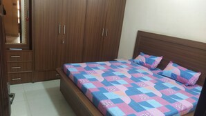 A bedroom with a bed, a wardrobe, and a tiled floor.