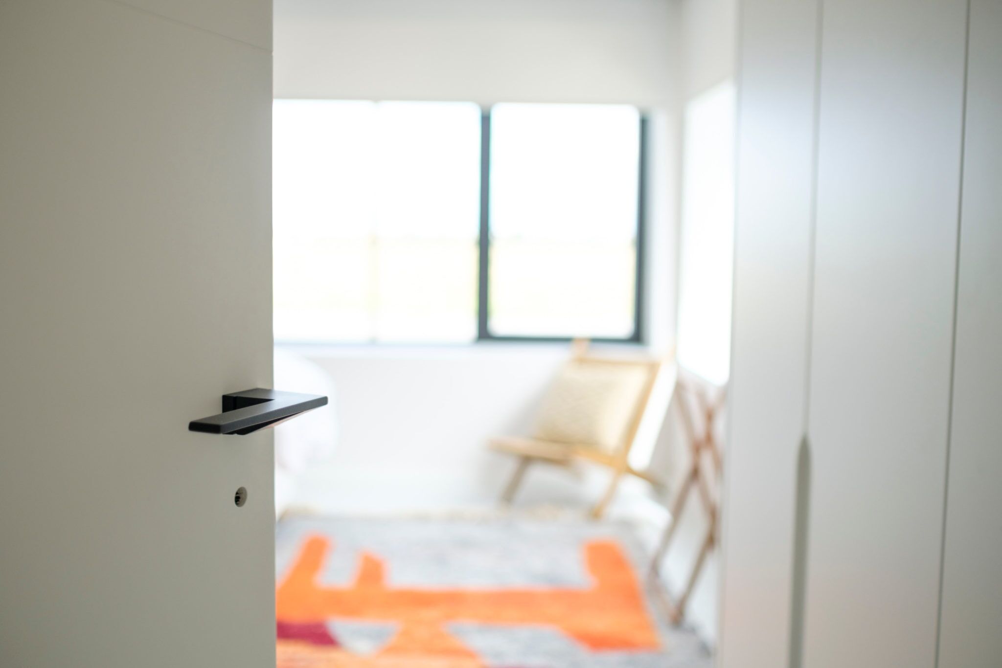A doorway leading to a room with a window and a chair.