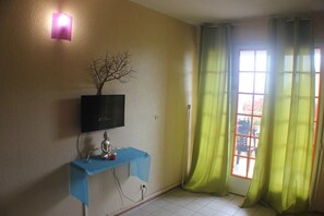 Enjoy a simple, functional space with a flat-screen TV, comfortable seating area, and large window with green curtains.