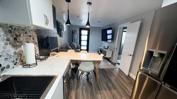A modern kitchen with a marble countertop, stainless steel appliances, and a dining area with a wooden table and chairs. - Luxury-Modern Suite /Cozy CO Vibes /Private Yard (Aurora)